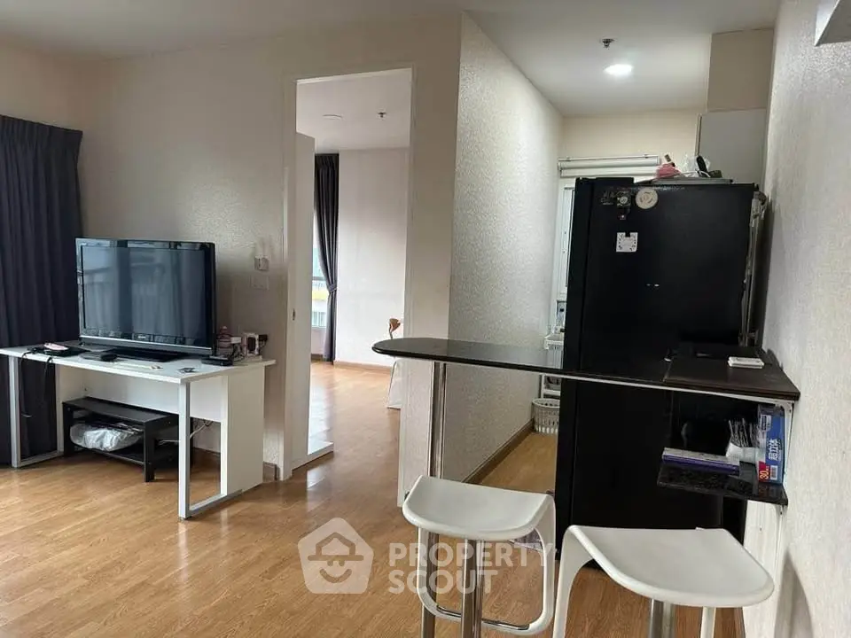 Modern living room with open layout and stylish furniture, featuring a sleek TV setup and bar counter.