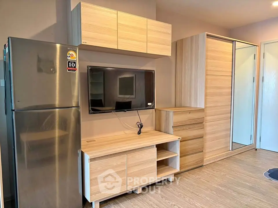 Modern living room with sleek wooden furniture and stainless steel fridge, perfect for contemporary living.