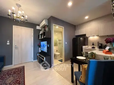 Modern open-plan living room with kitchen and dining area, featuring elegant lighting and stylish decor.