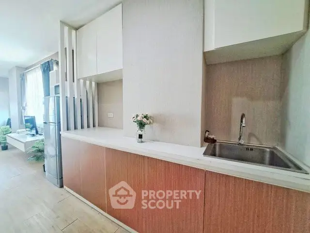 Modern kitchen with sleek cabinetry and integrated sink in a bright apartment.