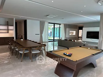 Luxurious open-plan living room with pool table and elegant dining area, perfect for entertainment.