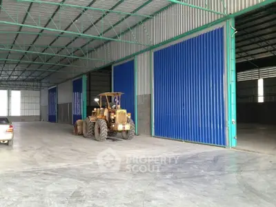 Spacious industrial warehouse with large blue sliding doors and ample interior space.