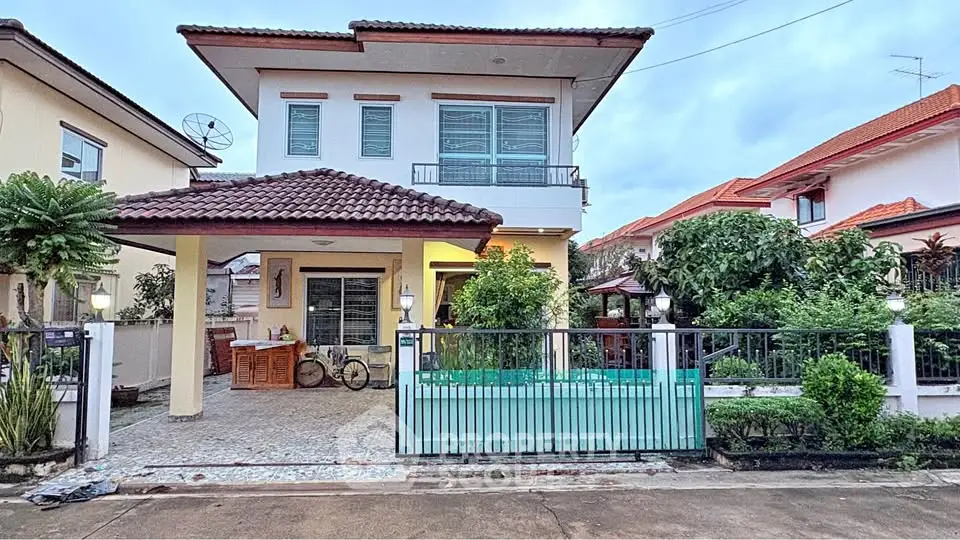 Charming two-story house with gated entrance and lush garden in a serene neighborhood.