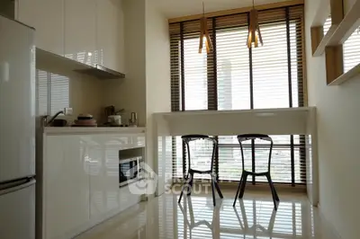 Modern kitchen with sleek cabinets and dining area with large windows.