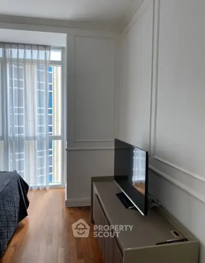 Modern bedroom with sleek TV setup and large window for natural light.