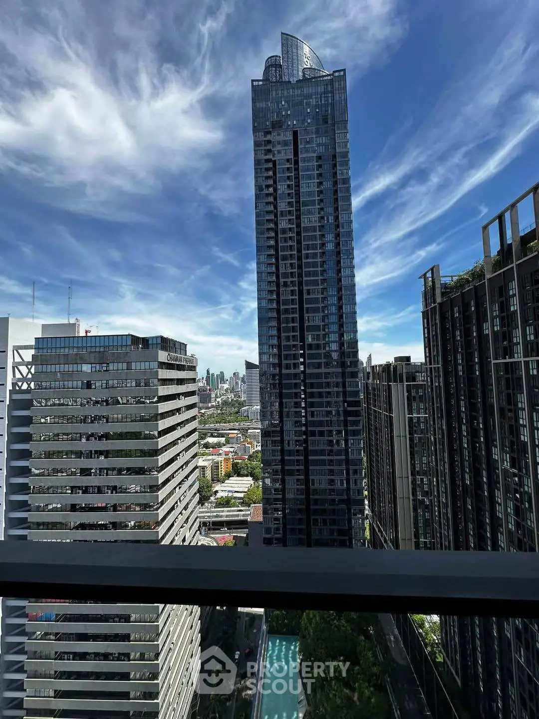 Stunning cityscape view from a high-rise balcony with modern skyscrapers and clear blue sky.