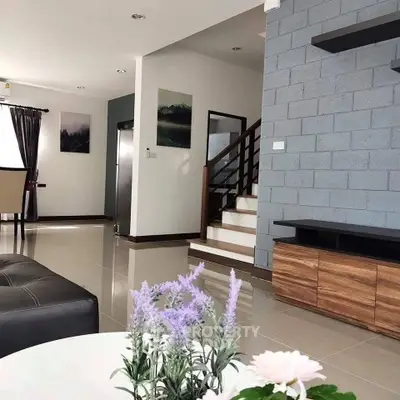 Modern living room with stylish decor and open layout, featuring a staircase and elegant furnishings.