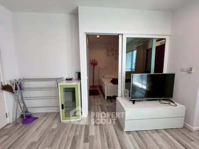 Modern apartment interior with TV and bedroom view, featuring sleek flooring and minimalist decor.