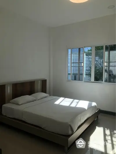 Bright minimalist bedroom with large window and modern bed frame