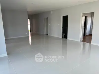 Spacious modern interior with glossy tiled floors and multiple doorways, ideal for open living concepts.
