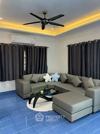 Stylish living room with modern gray sectional sofa and blue tiled floor, featuring elegant ceiling fan and ambient lighting.