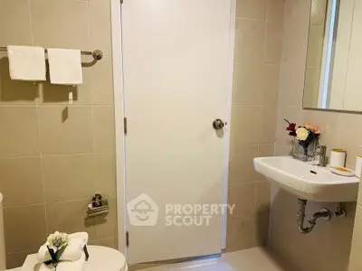 Modern bathroom with elegant fixtures and neutral tiles, featuring a sleek sink and stylish decor.