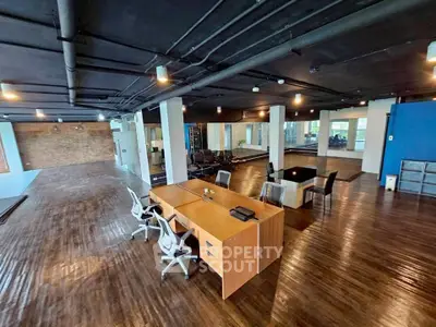 Spacious modern office space with sleek wooden flooring and stylish furniture, ideal for creative work environments.