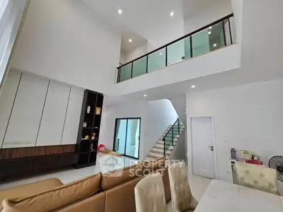 Spacious modern living room with high ceiling and elegant staircase