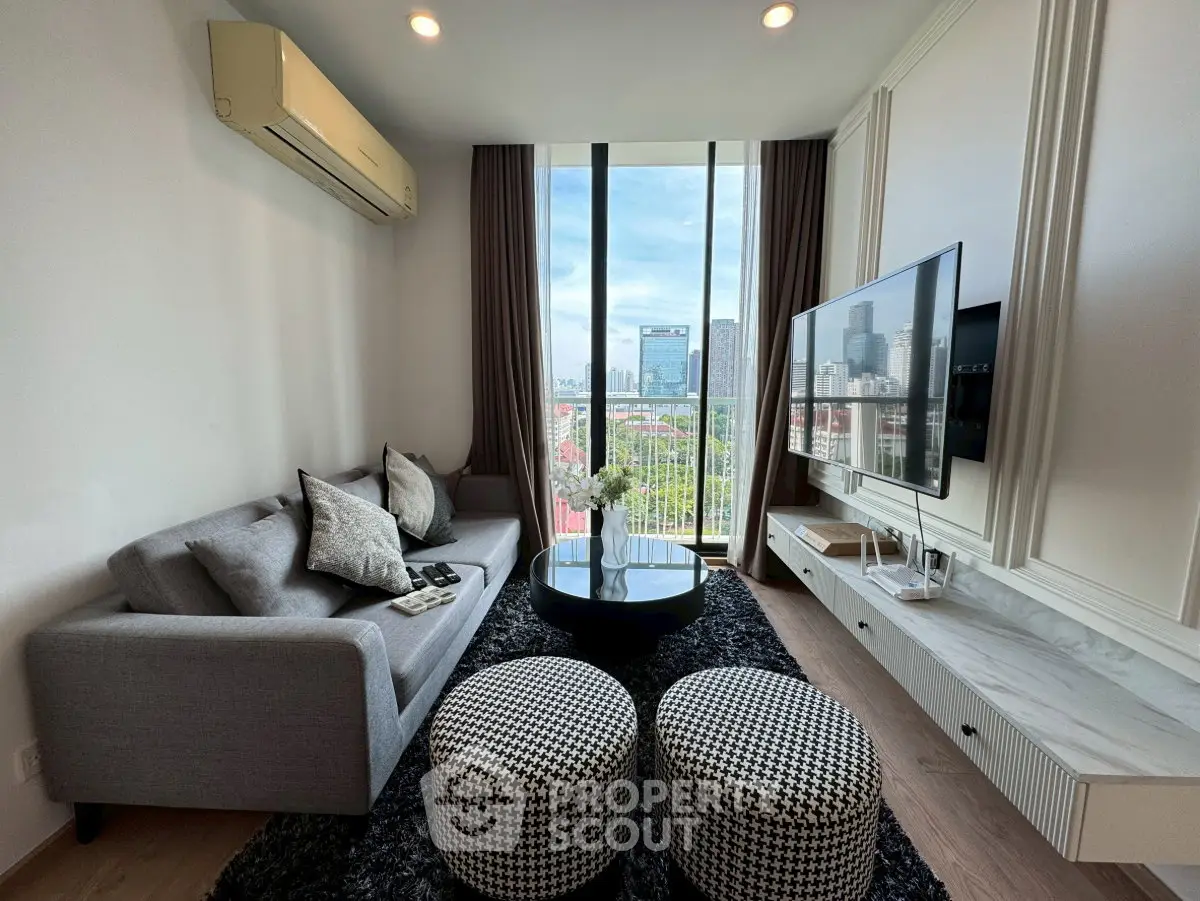 Modern living room with city view, featuring stylish furniture and large windows for natural light.