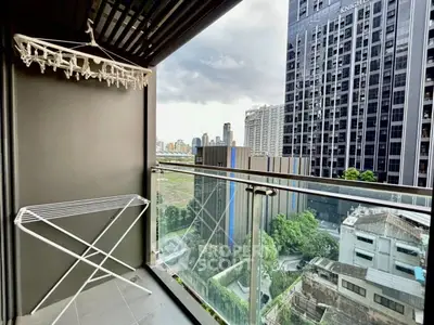Modern balcony with city view in high-rise building, featuring glass railing and drying rack.