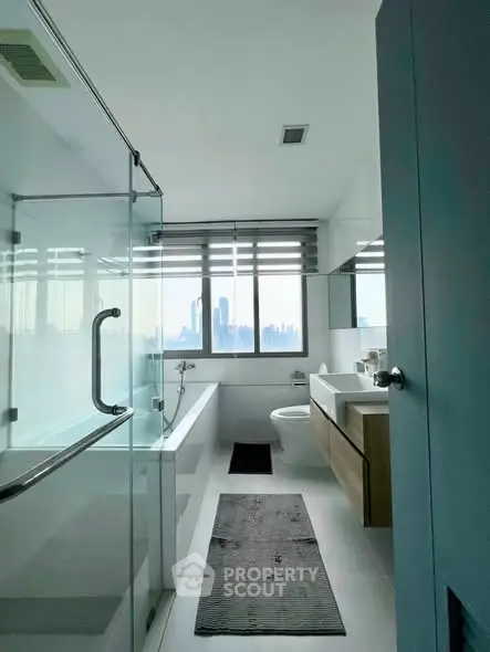 Modern bathroom with city view, featuring glass shower and sleek fixtures.