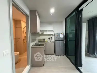 Modern compact kitchen with sleek cabinetry and adjacent bathroom in stylish apartment.