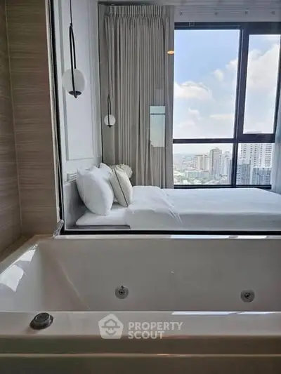Luxurious bedroom with bathtub and stunning city view through large windows.