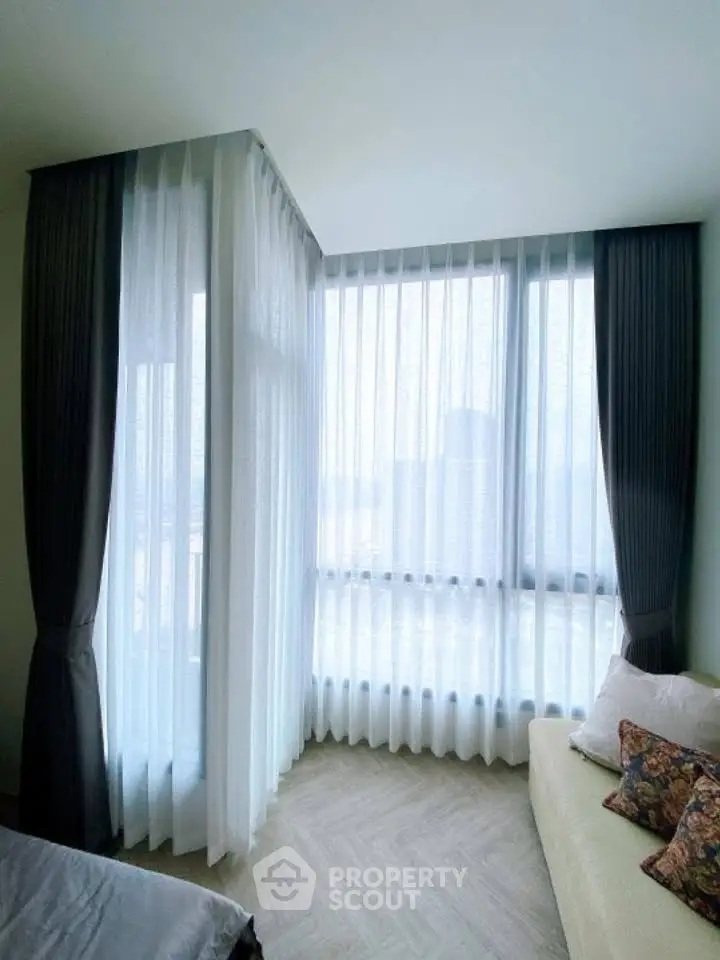 Bright corner unit with large windows and elegant curtains in a cozy living space.