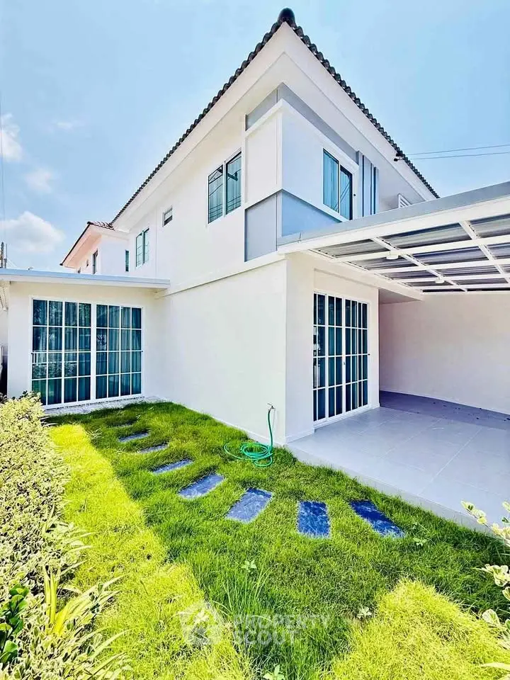 Modern two-story house with lush green lawn and spacious carport