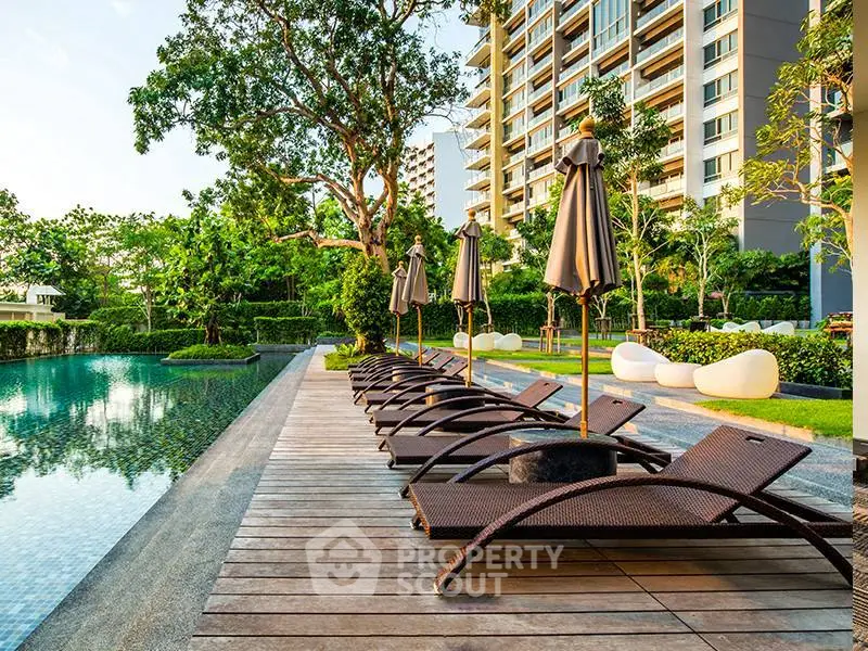 Luxurious poolside area with modern loungers and lush greenery in a high-end residential complex.
