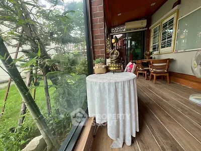 Charming garden view from a cozy balcony with wooden flooring and elegant decor.