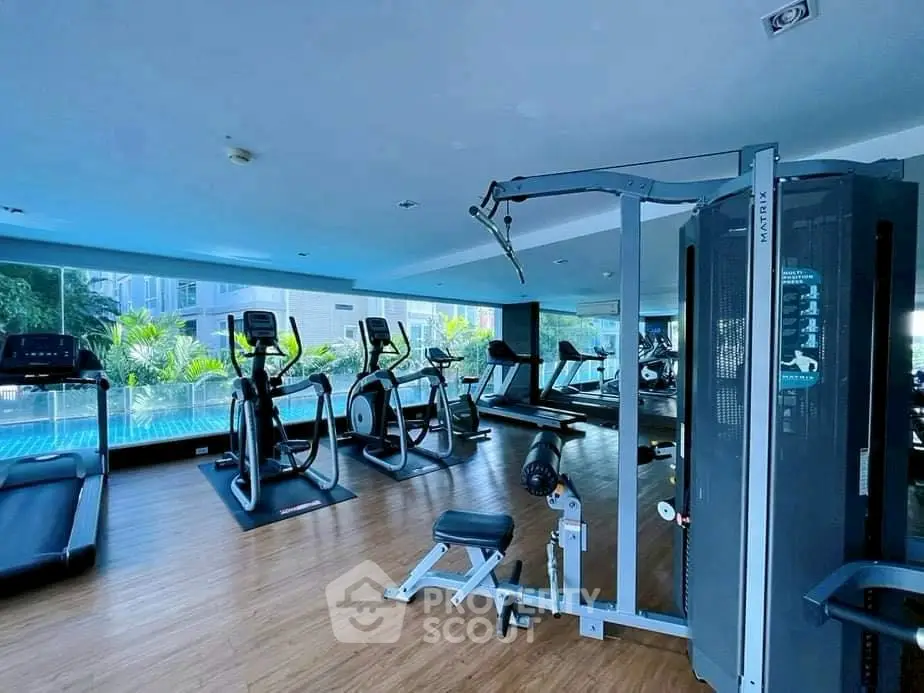 Modern gym with state-of-the-art equipment and pool view in luxury residential building.