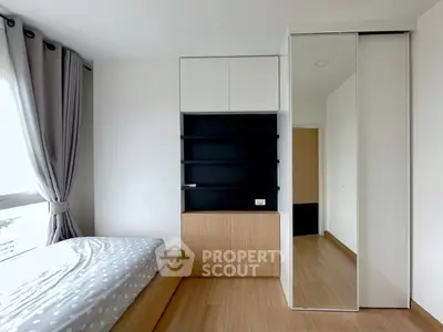 Modern bedroom with sleek built-in storage and large window for natural light.