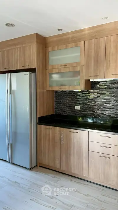 Modern kitchen with sleek wooden cabinets and stainless steel fridge