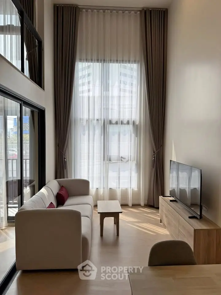 Spacious modern living room with high ceilings and large windows, featuring elegant curtains and contemporary furniture.