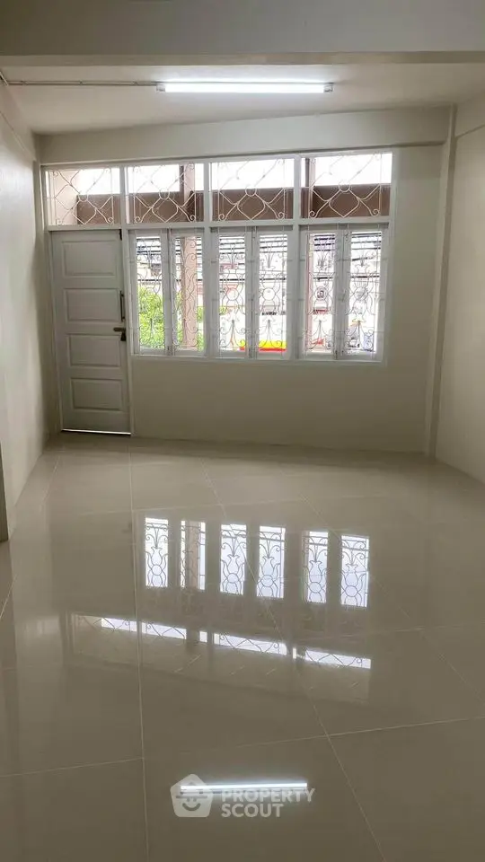 Spacious empty room with large windows and glossy tiled floor
