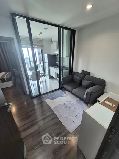 Modern apartment with open layout, featuring a cozy living area and sleek kitchen with glass partition.