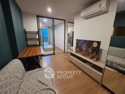 Modern living room with stylish decor and open layout, featuring a cozy sofa and flat-screen TV.