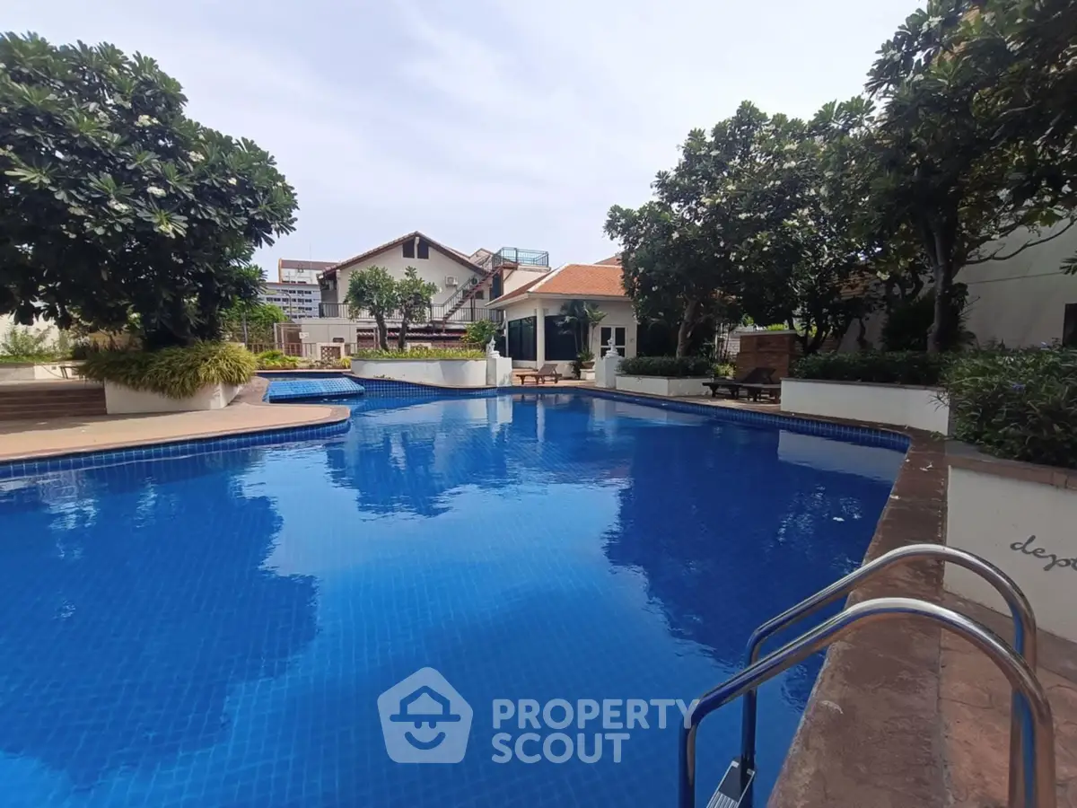 Luxurious residential pool area with lush greenery and modern amenities.