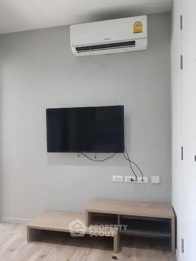 Modern living room with wall-mounted TV and air conditioning unit.