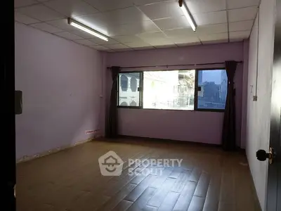 Spacious unfurnished room with large window and wooden flooring, ideal for customization.