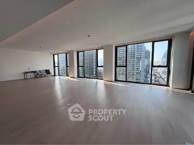 Spacious modern living room with large windows and city view, perfect for urban living.