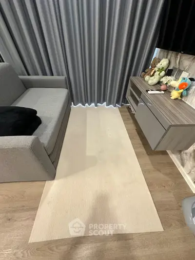 Modern living room with gray sofa, sleek cabinet, and plush toys on display.