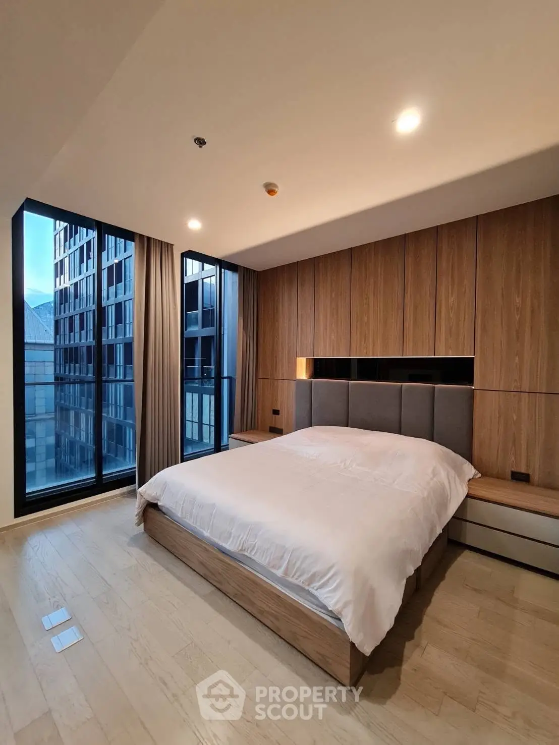 Modern bedroom with large windows and wooden accents in a luxury apartment.