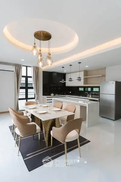 Modern kitchen with open layout and elegant dining area featuring stylish lighting and sleek appliances.