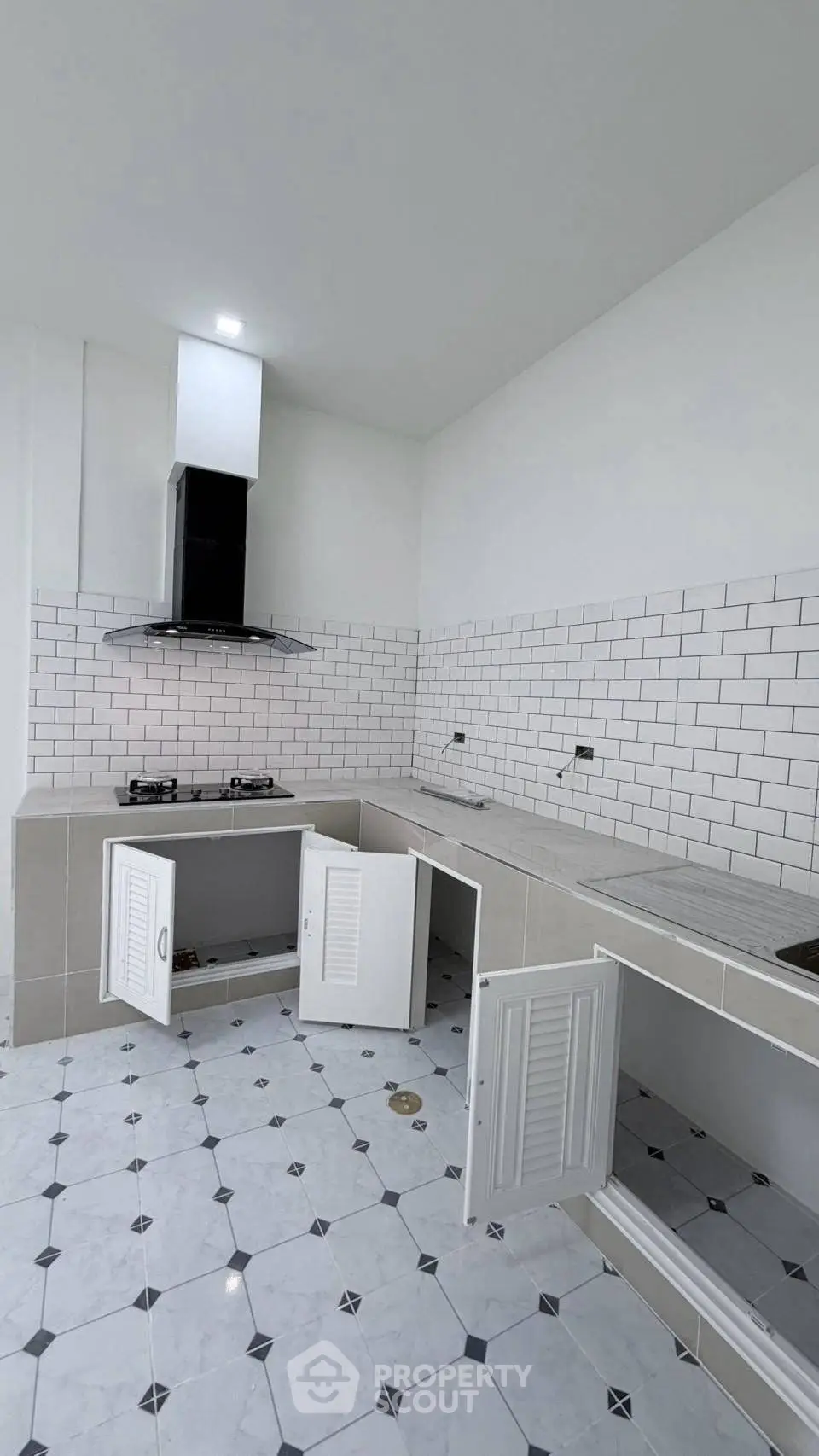 Modern kitchen with sleek white cabinetry and gas stove, featuring stylish subway tile backsplash.