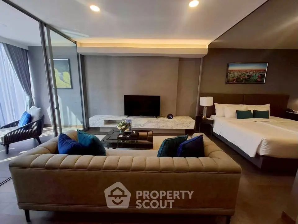 Luxurious open-plan living room with modern decor and spacious layout, featuring a cozy seating area and elegant bedroom.
