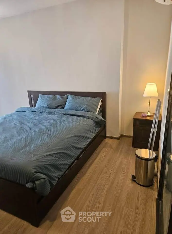 Cozy bedroom with wooden flooring, stylish bed, and ambient lighting for a relaxing atmosphere.