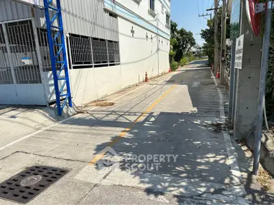 Quiet residential street with gated entrance and clear blue sky.