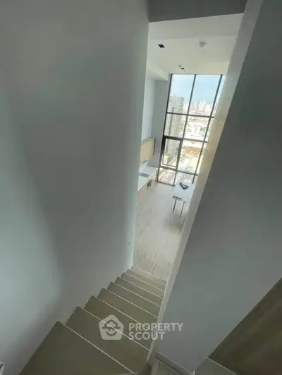 Modern loft apartment with high ceilings and large windows offering city views.