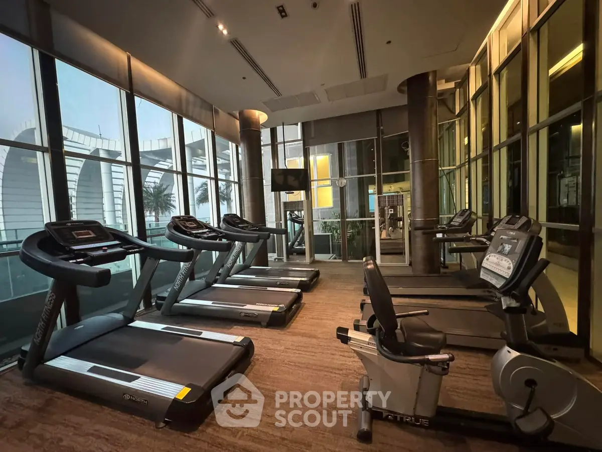Modern gym with state-of-the-art equipment and large windows offering a scenic view.