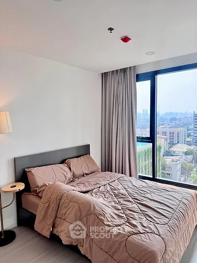 Modern bedroom with city view, featuring a cozy bed and large window for natural light.