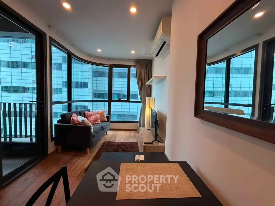 Modern living room with large windows and city view, featuring cozy seating and stylish decor.