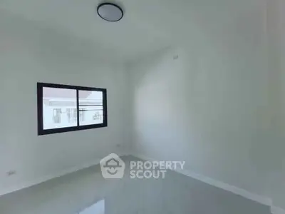 Spacious empty room with large window and modern ceiling light, perfect for customization.